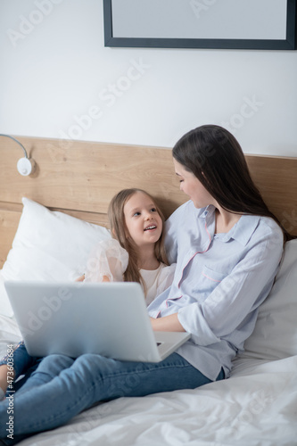 Female child and her mother sitting in the bedroom