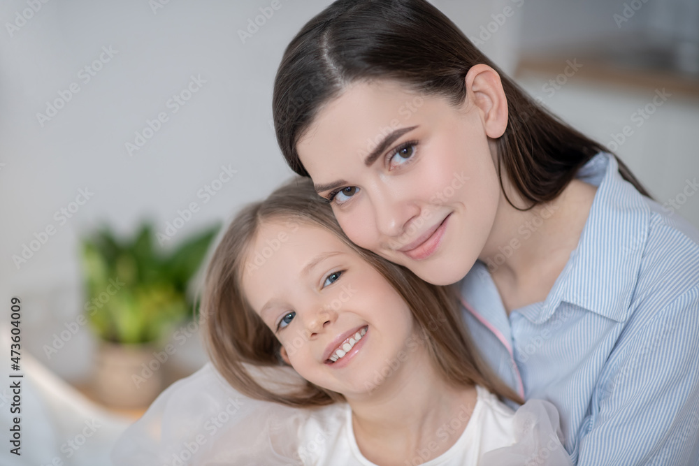 Happy mother and her joyful daughter posing for the camera Happy mother and her joyful daughter posing for the camera