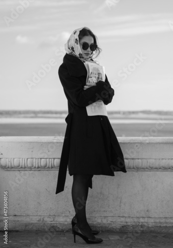 Black and white full-length portrait of a girl in a black coat