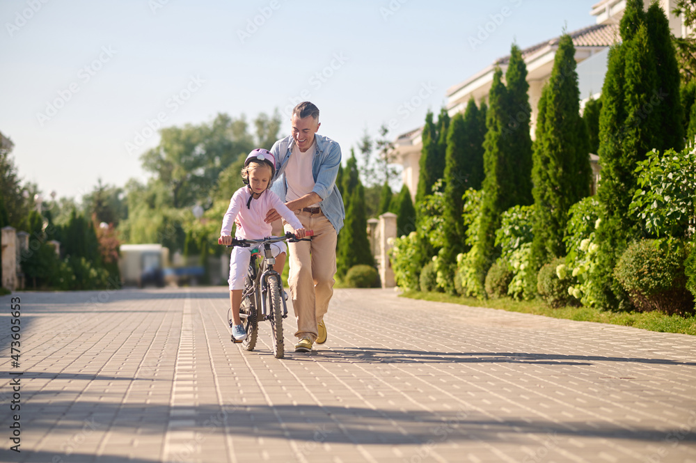 Dad riding a bike with his daughter sitting on it Dad riding a bike with his daughter sitting on it