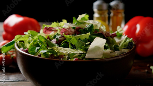 Mix of fresh green salad in a plate on the table with vegetables and spices.