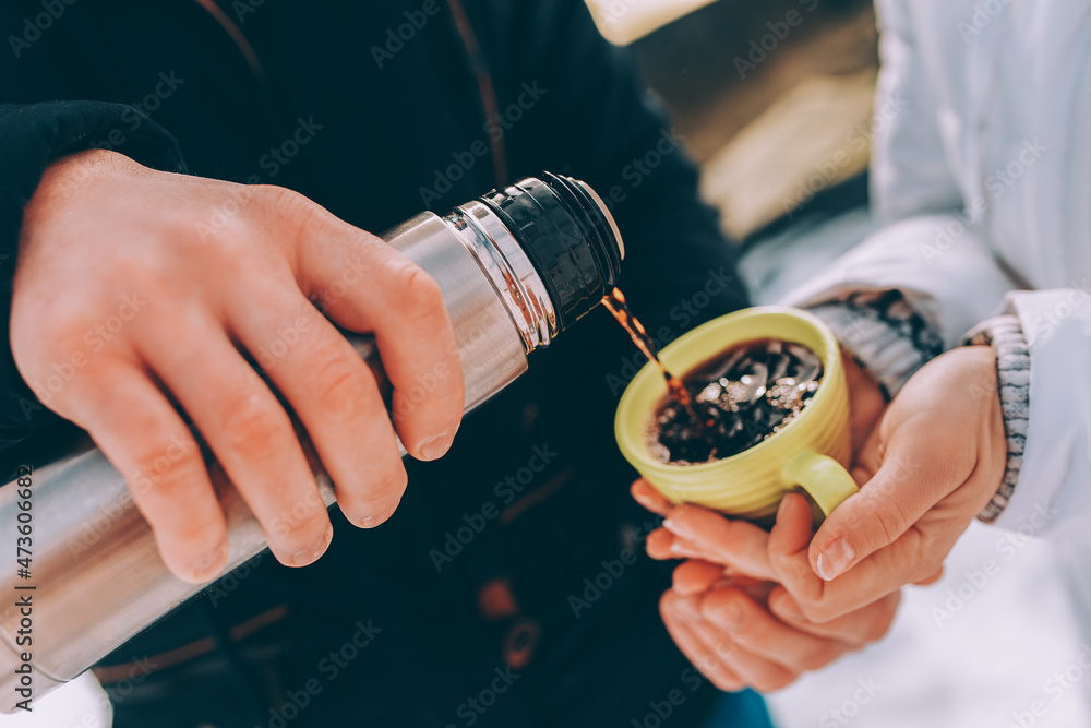 boy pours hot cacao to his girlfriend's green cup. winter theme