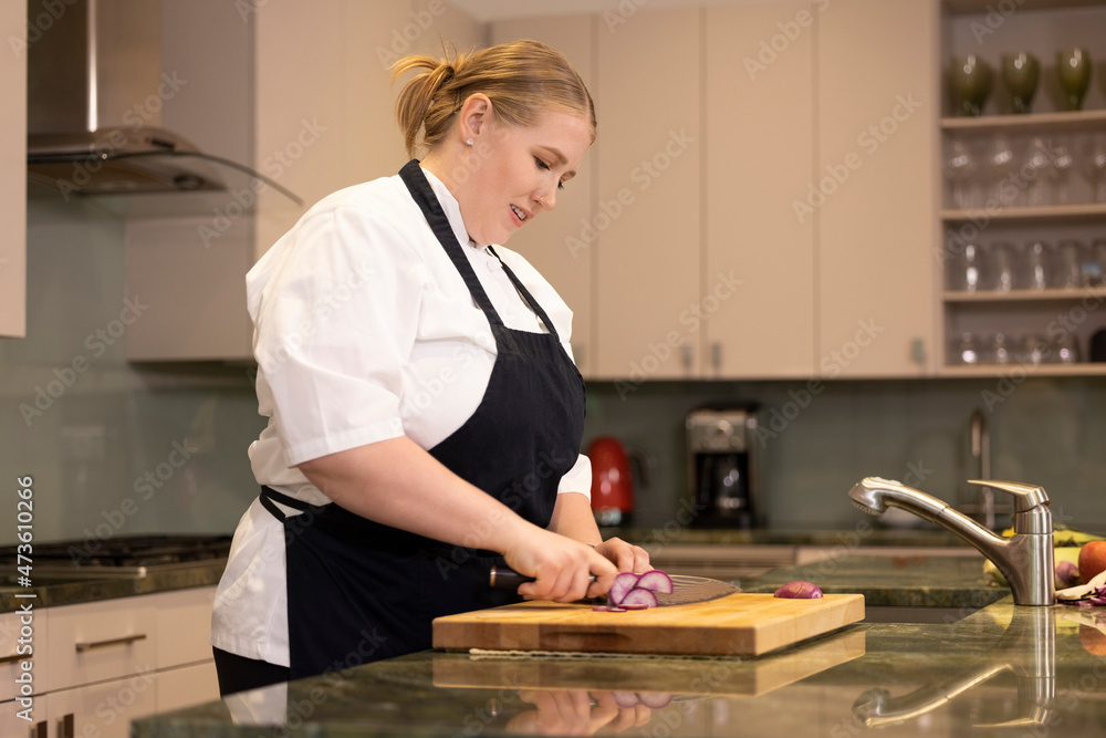 Professional Chef Megan Gill in home kitchen cutting a radish on cutting board Professional Chef Megan Gill in home kitchen cutting a radish on cutting board