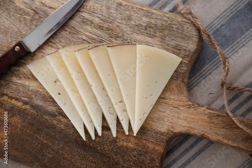 Slices of spanish manchego cheese on a wooden background photo