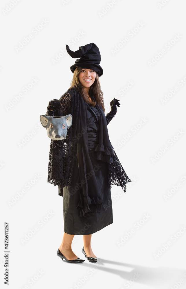 Full length shot of a Hispanic woman dressed as a witch for Halloween holding a mouse head trick or treat bucket dancing, against a white background Full length shot of a Hispanic woman dressed as a witch for Halloween holding a mouse head trick or treat bucket dancing, against a white background