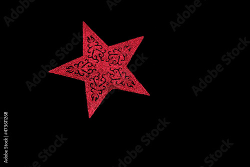 Christmas tree decoration in the form of a red star isolated on black. Red star on black background.