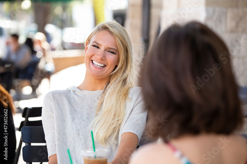Two friends sitting outside a cafe laughing photo