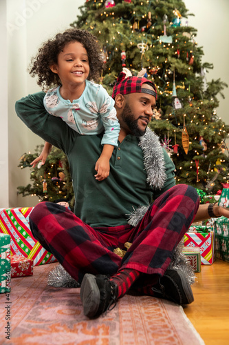 Happy family with Christmas presents sitting in front of illuminated tree.  photo