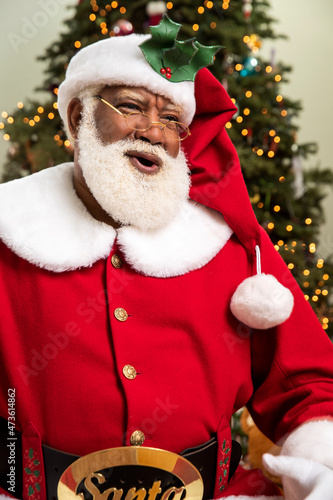 Santa Claus laughing and looking off camera against Christmas background photo
