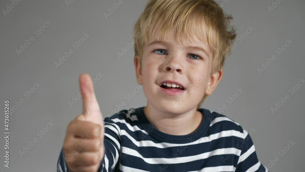 Child Shows Thumbs Up Gesture. Portrait Cute Little Boy. Happy Facial Expression Emotion Glad Smiling Face. Kid against White Wall Background. 2x Slow motion 4K Child Shows Thumbs Up Gesture. Portrait Cute Little Boy. Happy Facial Expression Emotion Glad Smiling Face. Kid against White Wall Background. 2x Slow motion 4K