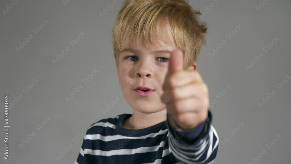 Child Shows Thumbs Up Gesture. Portrait Cute Little Boy. Happy Facial Expression Emotion Glad Smiling Face. Kid against White Wall Background. 2x Slow motion 4K Child Shows Thumbs Up Gesture. Portrait Cute Little Boy. Happy Facial Expression Emotion Glad Smiling Face. Kid against White Wall Background. 2x Slow motion 4K