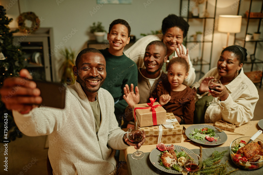 Obraz premium High angle portrait of happy African-American family taking selfie photo while enjoying Christmas at home together