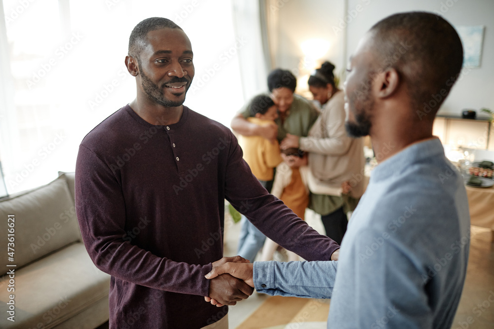Obraz premium Waist up portrait of smiling African-American man welcoming guests for dinner party at home