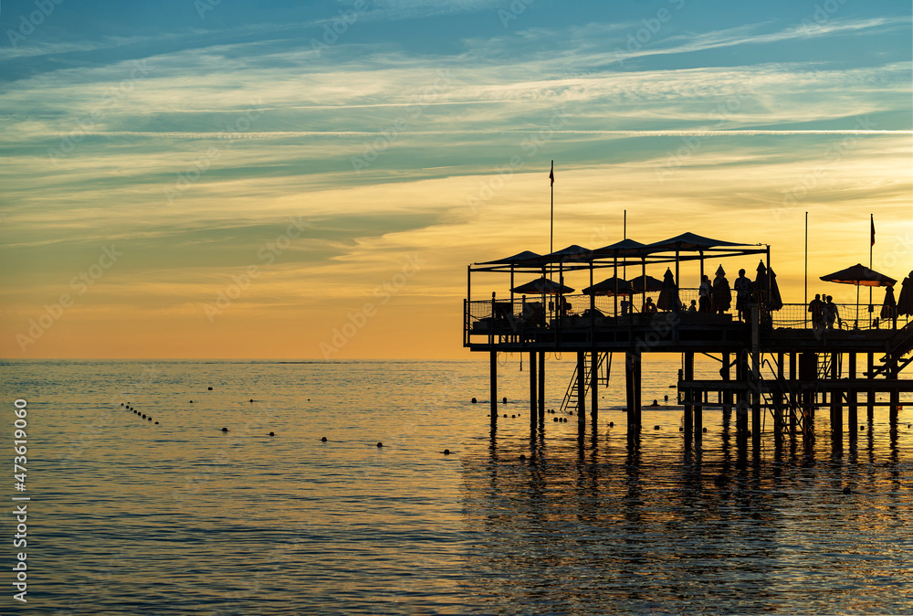 beautiful sunset on the sea. pier with umbrellas and sunbeds for vacationers