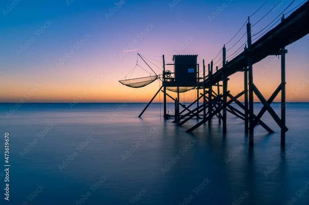 Typical old wooden fishing huts on stilts called « carrelet » in the atlantic ocean near La Rochelle, France. shot taken at sunset.