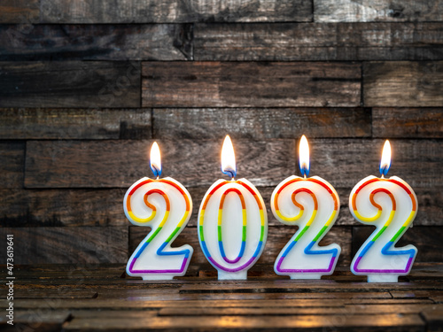 Colorful 2022 candles burning against a rustic wood background, Happy New Year holiday concept.