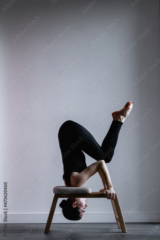 Girl doing fit exercises on pilates yoga shoulder stand chair