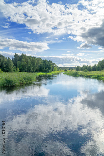 Landscape Suprasl River in Podlasie, Poland. The river flows among meadows and forests, the blue sky with white clouds is reflected in the water. Sunny summer day, nobody. © msnobody
