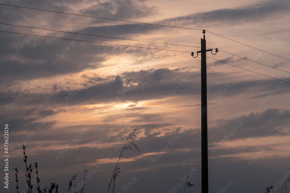 Old fashioned pylon for power supply against sunset sky