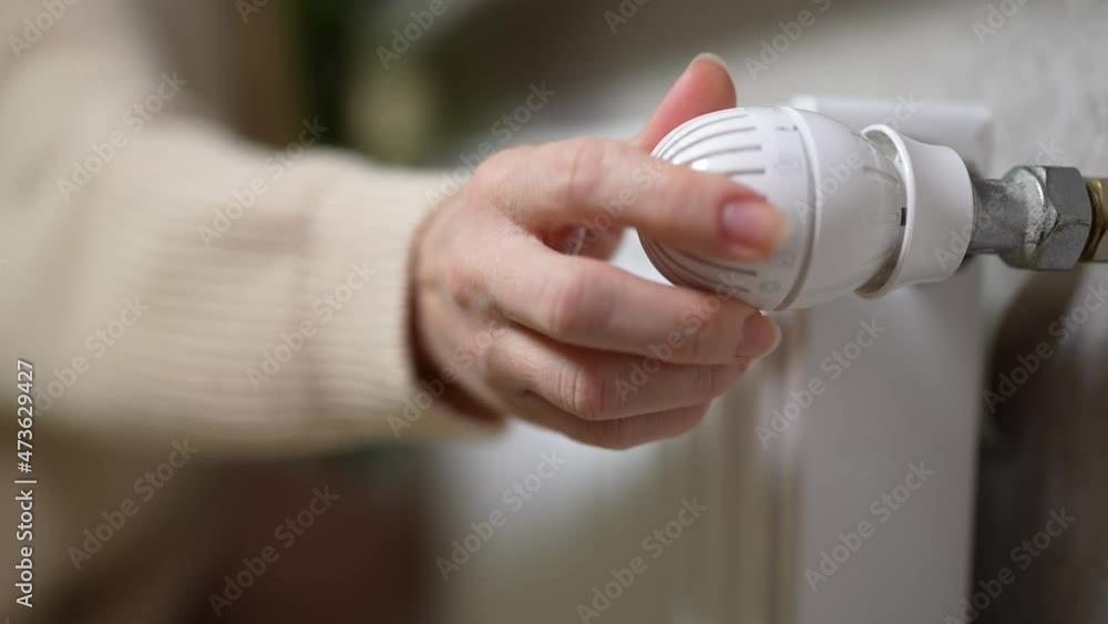 female hands touch the cold radiator of the battery and open the valve to escape the cold at home. female hands touch the cold radiator of the battery and open the valve to escape the cold at home.