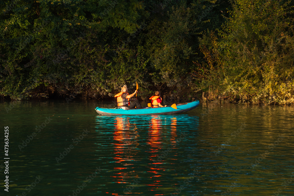 Grandfather with grandson kayaking in Marne river at autumn at sunset (France)