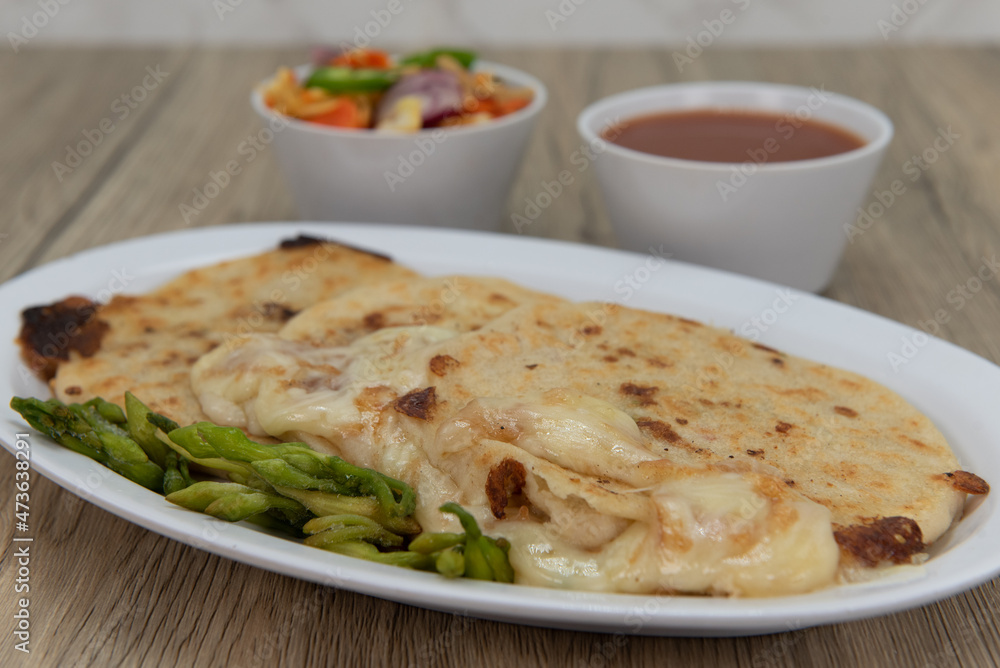 Three round pupusas served with salsa and dipping sauce as a Latino food delicacy Three round pupusas served with salsa and dipping sauce as a Latino food delicacy