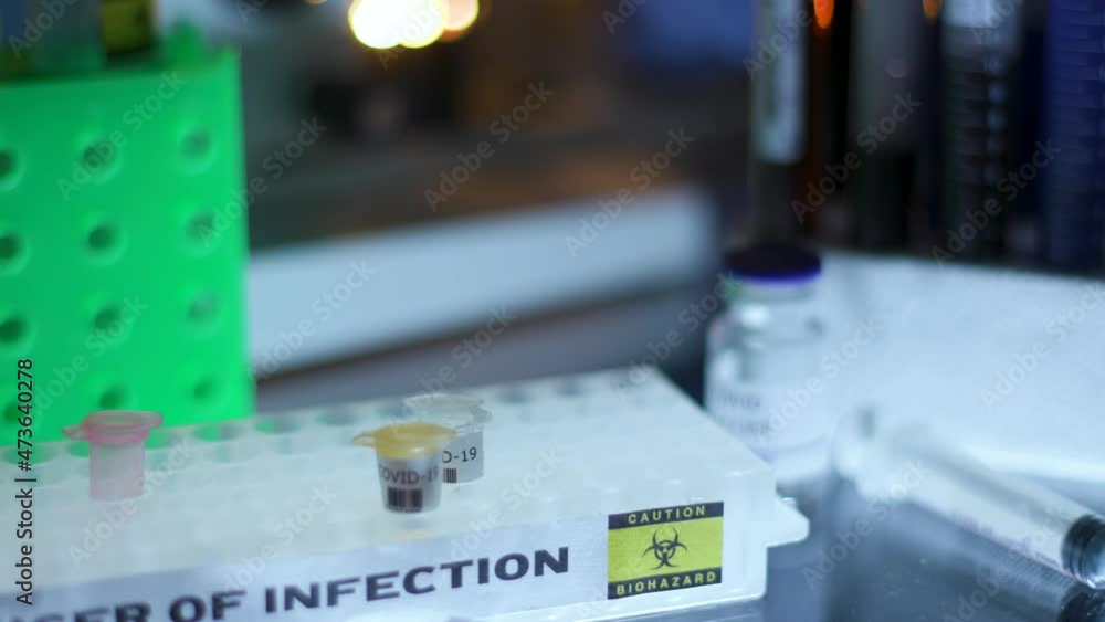 A medical laboratory technician or virologist places a snap-lock vial with a sample of Coronavirus variant strain in a microtube rack. A medical laboratory technician or virologist places a snap-lock vial with a sample of Coronavirus variant strain in a microtube rack.