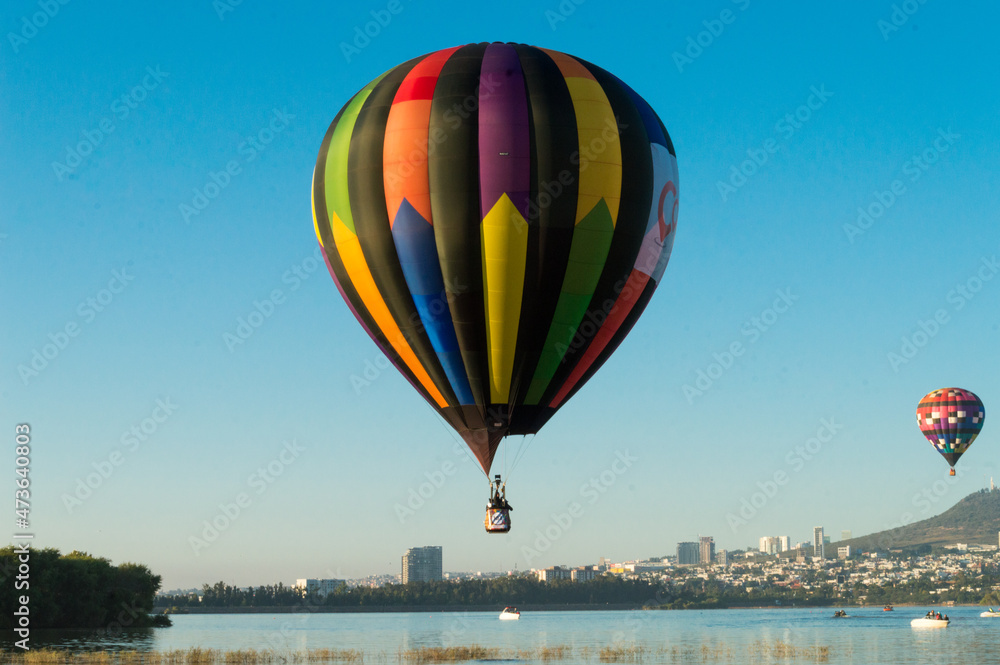 Fototapeta premium Globo aerostático volando sobre un lago