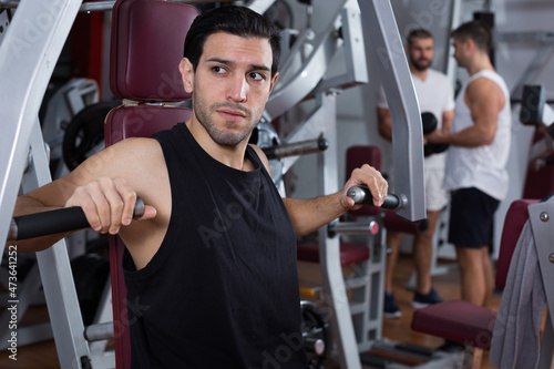 Portrait of athletic man during workout with power exercise machine in gym club