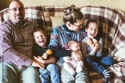 Family sitting on a couch and everyone is laughing
