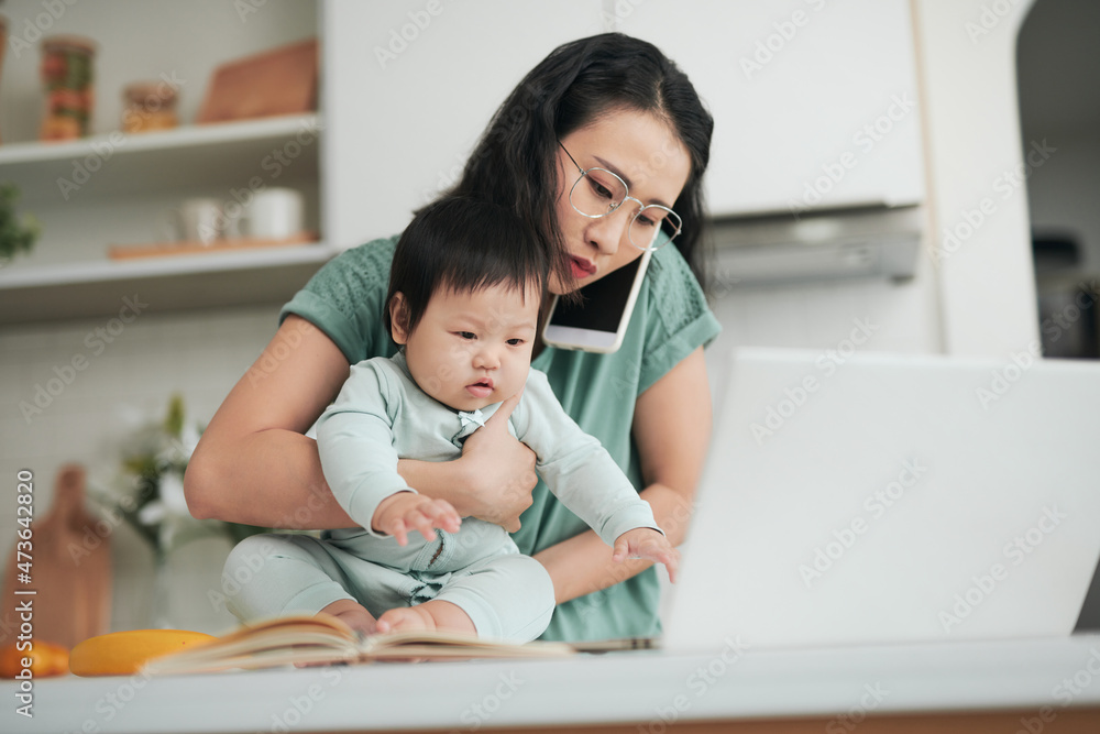 Stay home. Pretty young female using laptop working remotely during quarantine, her infant daughter not going to kindergarten too. Stay home. Pretty young female using laptop working remotely during quarantine, her infant daughter not going to kindergarten too.