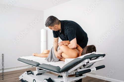 Physical therapist twisting back of patient photo