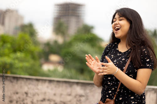 A young Indian girl making fun and clapping at outdoors photo