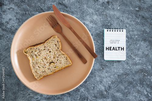 gut health notepad next to wholegrain multiseeds slice of bread on dining plate with fork and knife, healthy nutrition research about the microbiome photo