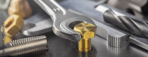 Wrench tightens brass bolt in steel billet. Spanner, bolt, screw and nuts.
