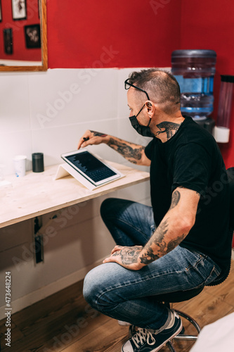 Tattoo artist looking at design photo