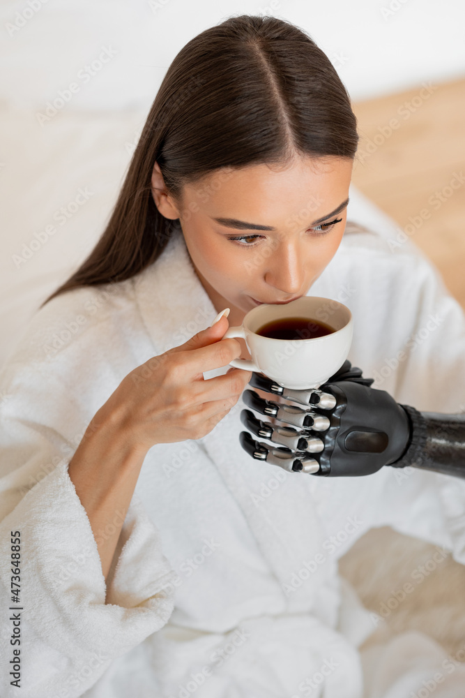 Girl with a prosthesis on her arm drinks coffee Girl with a prosthesis on her arm drinks coffee