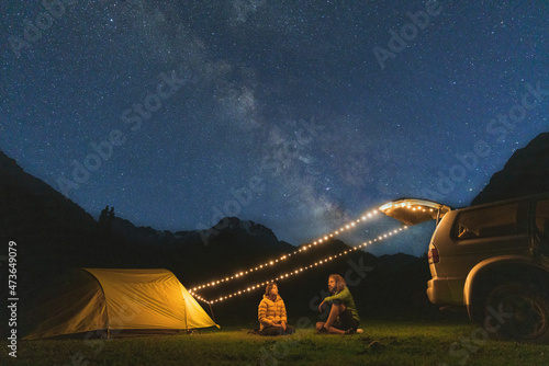 Couple sitting in camping under the starry sky photo