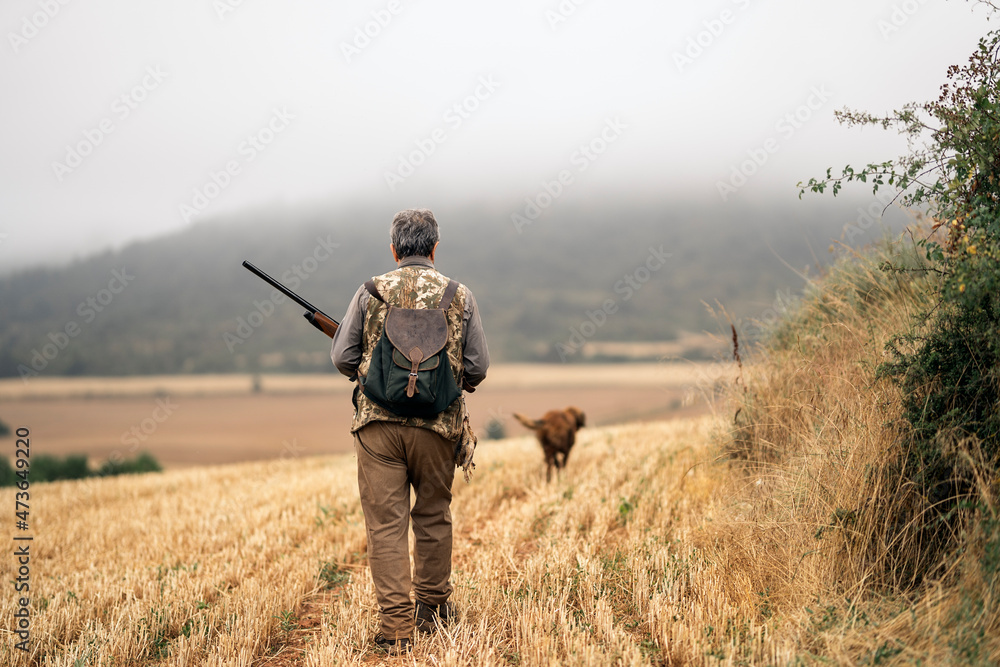 Hunter man and his dog walking on field Hunter man and his dog walking on field