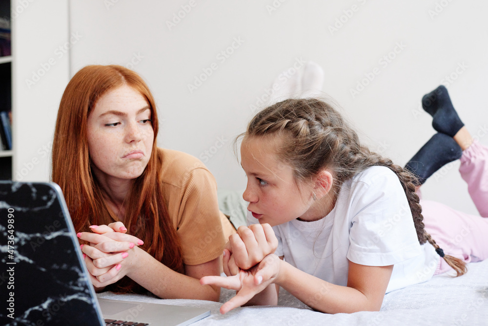 Pretty adult girl helping sister doing homework Pretty adult girl helping sister doing homework