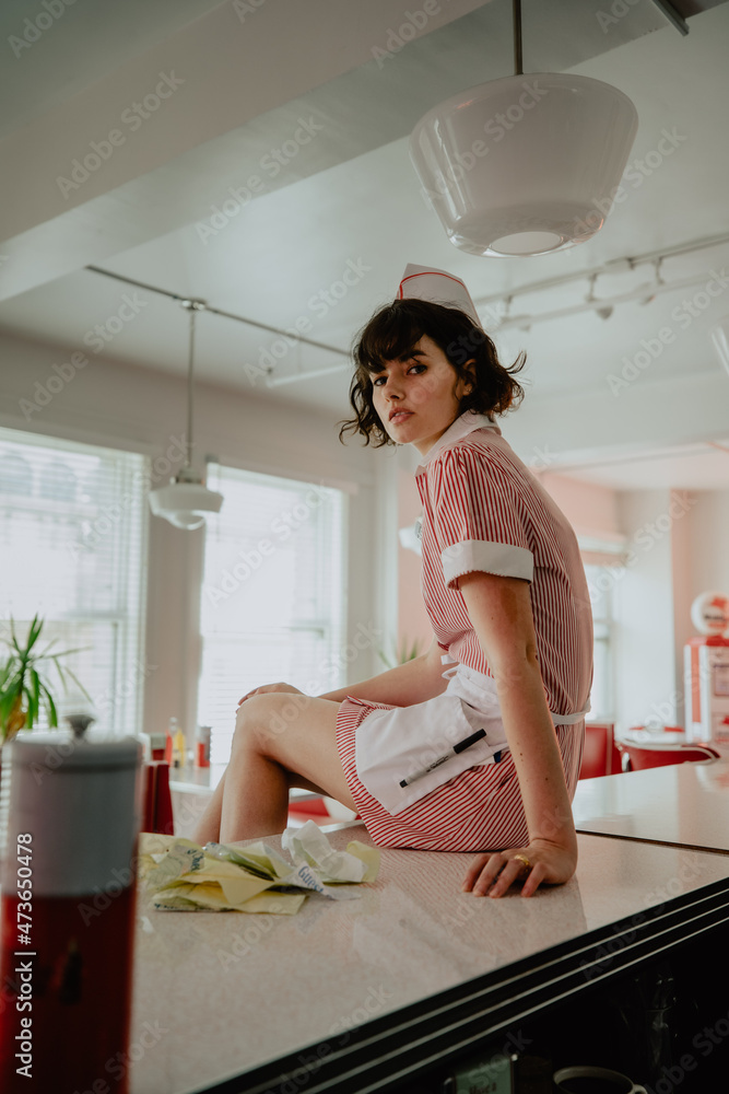 Waitress Sitting Atop Retro Diner's Counter Waitress Sitting Atop Retro Diner's Counter