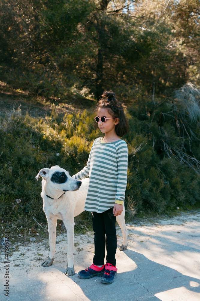 Kid and dog standing on path outdoors in sunlight Kid and dog standing on path outdoors in sunlight