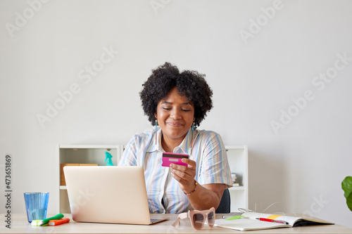 Smiling black employee shopping online at workplace photo