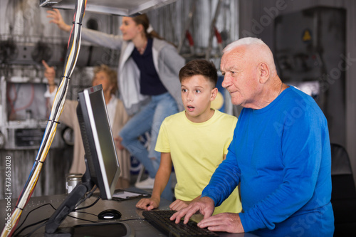 Teenager together with elderly grandfather looking for puzzle solution in quest room