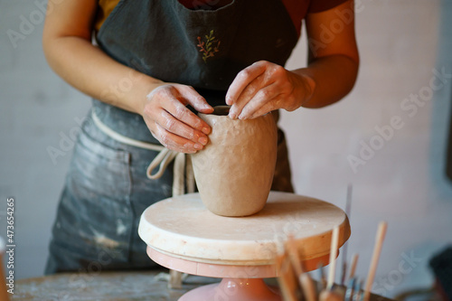 Stampa su tela Focus on art and handicraft: cropped image of female concentrated sculpturing potter tableware in studio