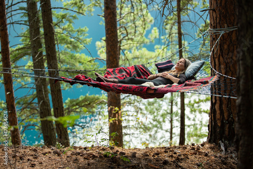 Woman meditating in hammock in forest photo