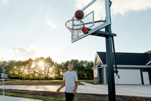 Teenager watching basketball enter hoop.  photo