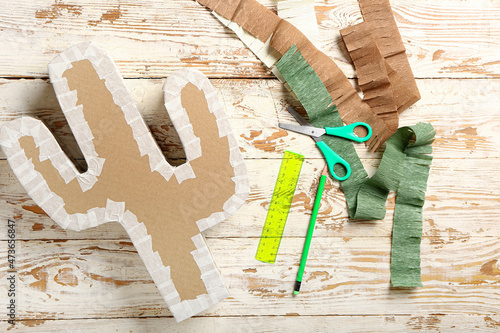Preparation of Mexican pinata on white wooden background