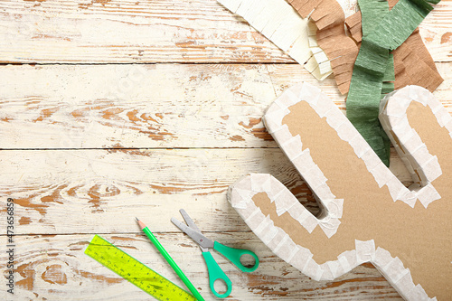 Preparation of Mexican pinata on white wooden background