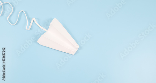 White paper plane with a lace trail on the left on a blue background